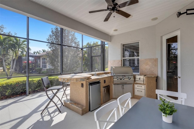 view of patio featuring ceiling fan, an outdoor kitchen, grilling area, and a wet bar