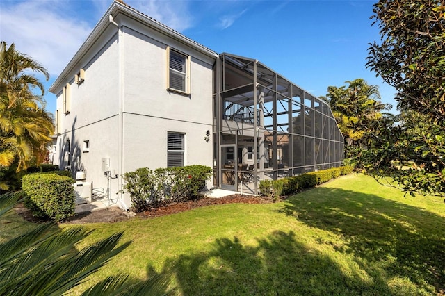 rear view of house with glass enclosure and a lawn