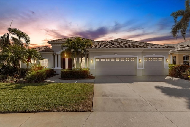 mediterranean / spanish-style home with a garage and a lawn