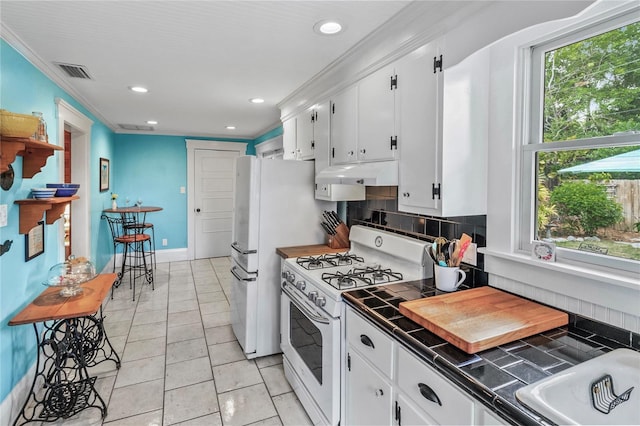 kitchen with white cabinets, ornamental molding, tile counters, decorative backsplash, and gas range gas stove