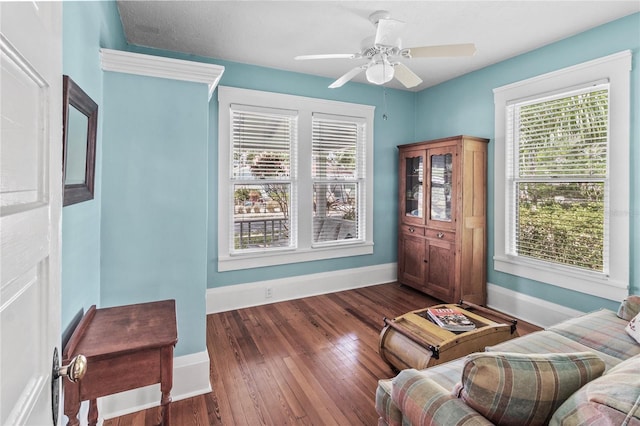 sitting room with dark wood-type flooring and ceiling fan