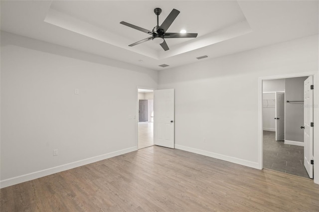 spare room with ceiling fan, a raised ceiling, and wood-type flooring