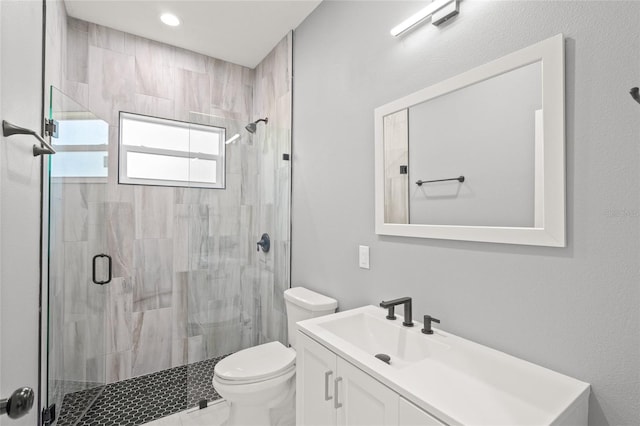 bathroom with a shower with shower door, vanity, and toilet