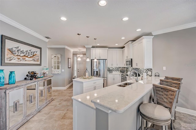 kitchen with stainless steel appliances, a peninsula, a sink, white cabinetry, and hanging light fixtures