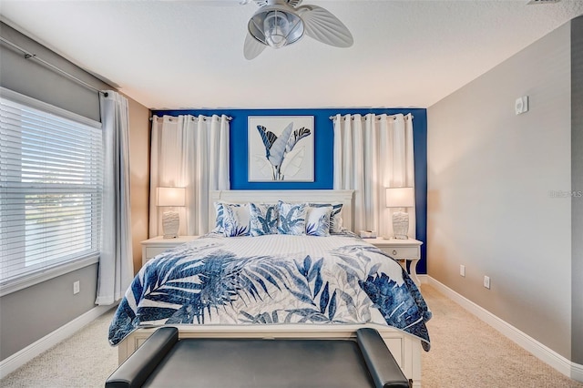 bedroom featuring ceiling fan, baseboards, and light colored carpet