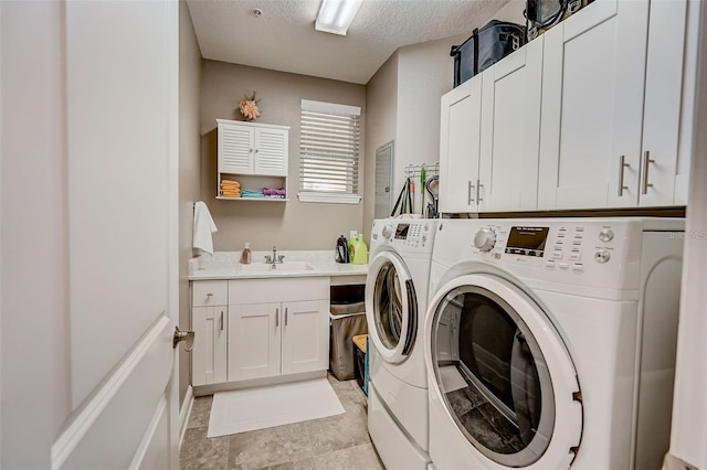 laundry area with washer and dryer, cabinet space, a sink, and a textured ceiling