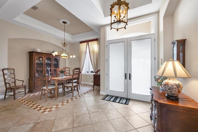 entrance foyer featuring an inviting chandelier, light tile patterned floors, a raised ceiling, and french doors