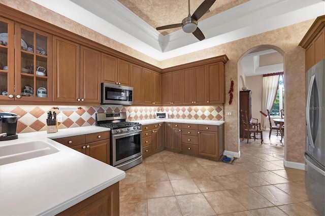 kitchen with appliances with stainless steel finishes, tasteful backsplash, sink, ceiling fan, and crown molding