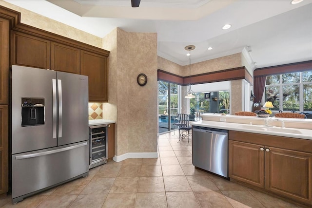 kitchen with appliances with stainless steel finishes, pendant lighting, sink, wine cooler, and a healthy amount of sunlight