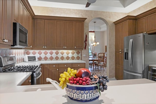 kitchen with appliances with stainless steel finishes, sink, backsplash, ceiling fan, and a raised ceiling