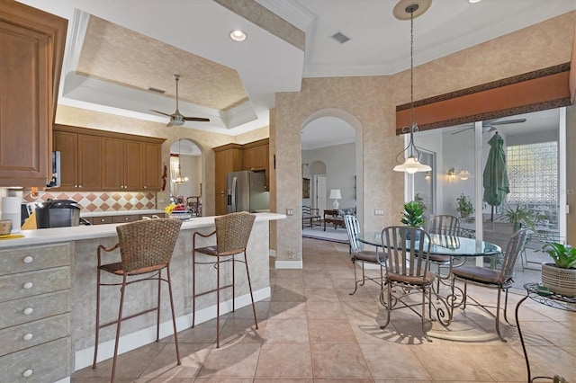 kitchen featuring stainless steel fridge with ice dispenser, decorative light fixtures, ceiling fan, kitchen peninsula, and crown molding