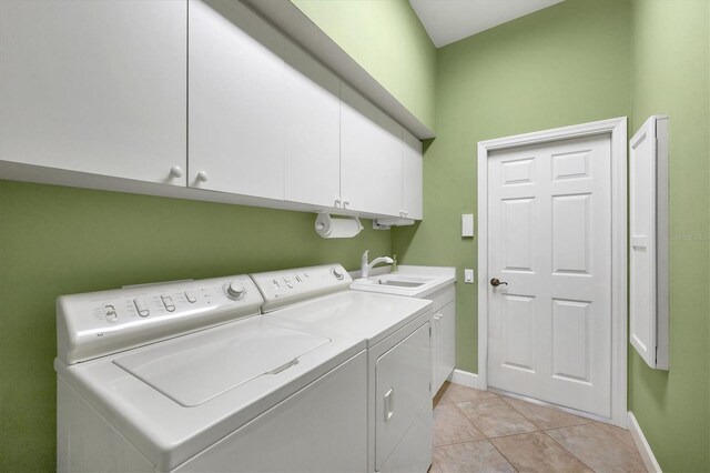 clothes washing area featuring independent washer and dryer, cabinets, sink, and light tile patterned floors