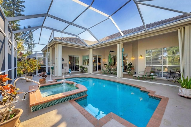 view of swimming pool with an in ground hot tub, pool water feature, ceiling fan, glass enclosure, and a patio area