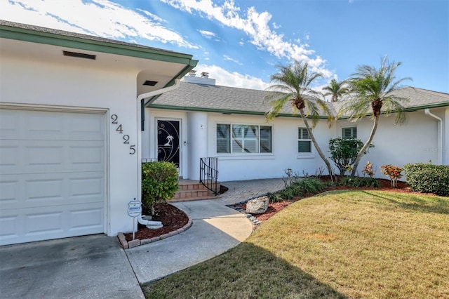 property entrance with a garage and a yard