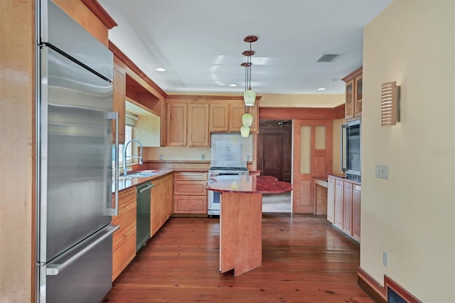 kitchen featuring pendant lighting, a center island, high end appliances, sink, and dark hardwood / wood-style floors