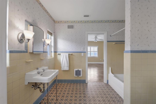 bathroom with shower / bathing tub combination, sink, tile walls, ceiling fan, and heating unit