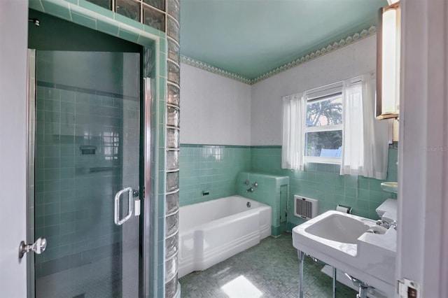 bathroom with tile patterned flooring, sink, tile walls, and plus walk in shower