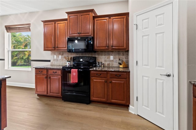 kitchen with dark stone countertops, tasteful backsplash, and black appliances