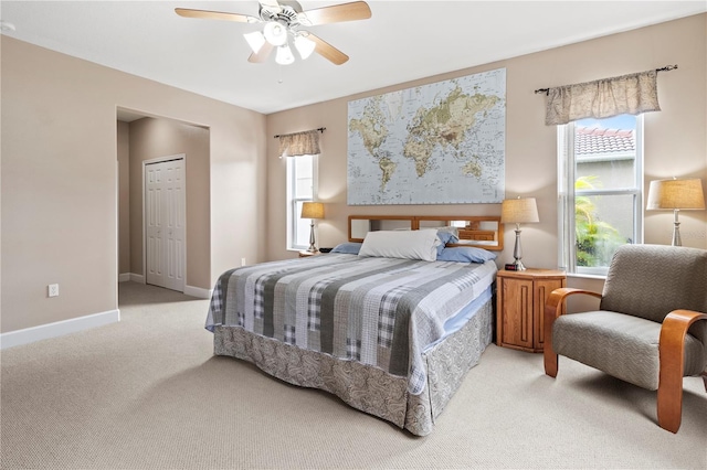 bedroom with ceiling fan, light colored carpet, and a closet