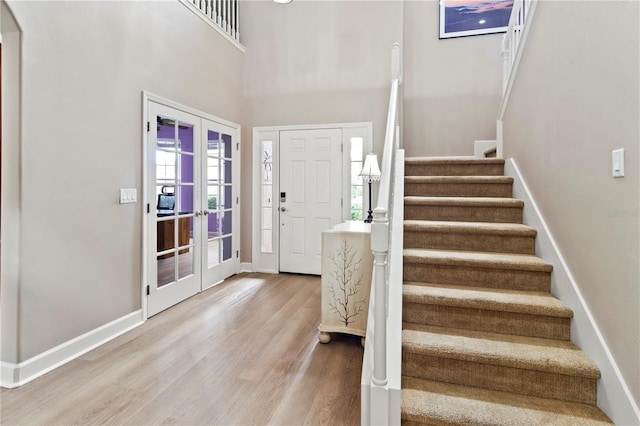 foyer entrance with a high ceiling, wood-type flooring, and french doors