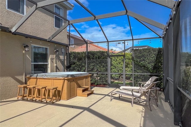 view of patio featuring glass enclosure, exterior bar, and a hot tub