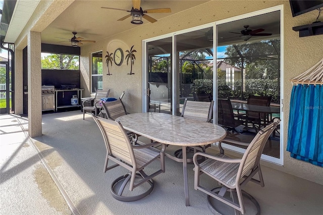 view of patio / terrace featuring ceiling fan, glass enclosure, and exterior kitchen