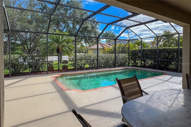 view of pool with glass enclosure and a patio area