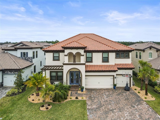 mediterranean / spanish home with a garage, a front lawn, decorative driveway, and stucco siding