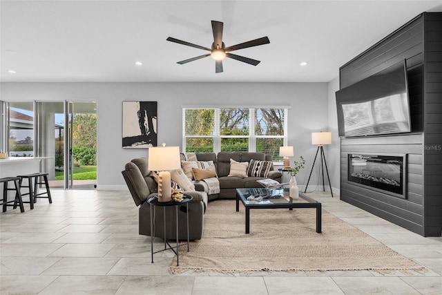 living room featuring ceiling fan, a wealth of natural light, and a large fireplace