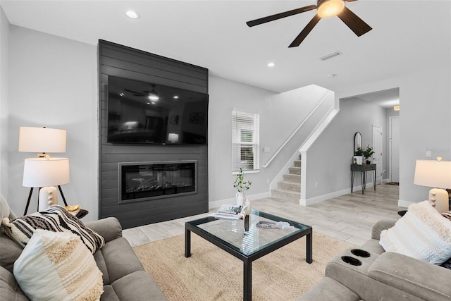 living room with ceiling fan and a fireplace