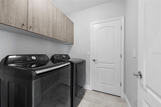 washroom featuring light tile patterned floors, cabinets, and washer and clothes dryer