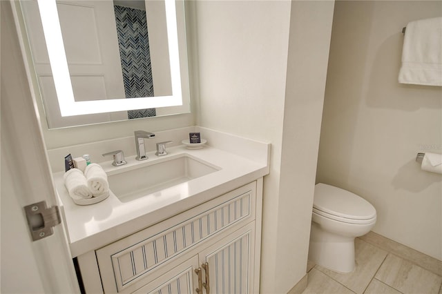 bathroom with toilet, vanity, and tile patterned flooring