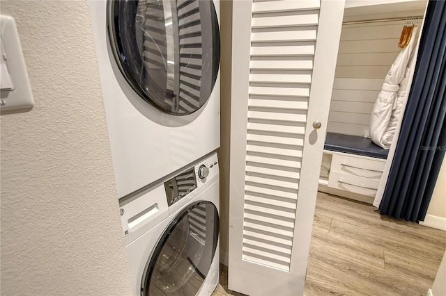 laundry area with stacked washer and clothes dryer and light hardwood / wood-style flooring