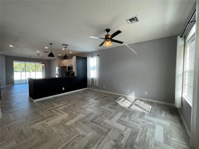 unfurnished living room featuring light parquet floors, ceiling fan, and a healthy amount of sunlight