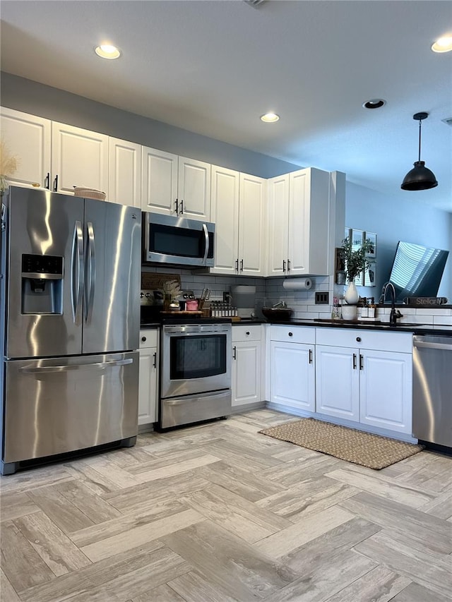 kitchen featuring stainless steel appliances, light parquet floors, tasteful backsplash, and white cabinetry