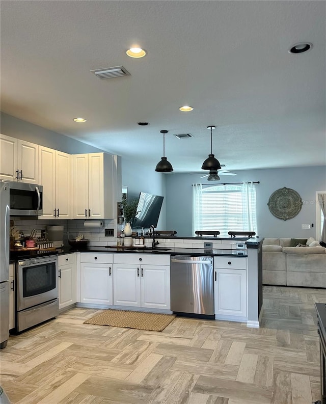 kitchen featuring sink, appliances with stainless steel finishes, light parquet floors, and hanging light fixtures