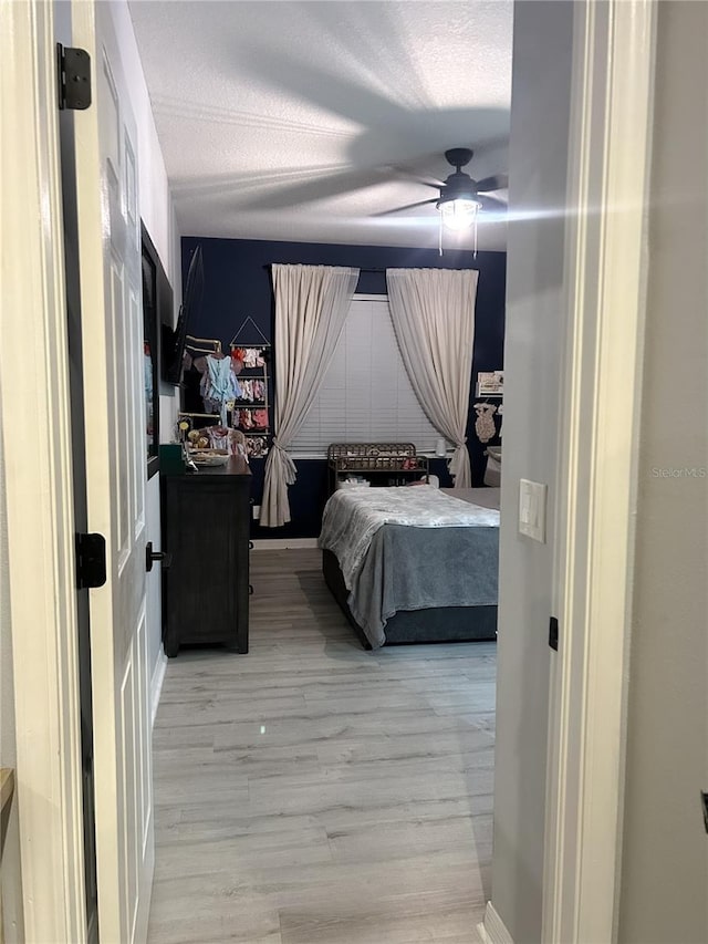 bedroom featuring a textured ceiling, ceiling fan, and light hardwood / wood-style floors