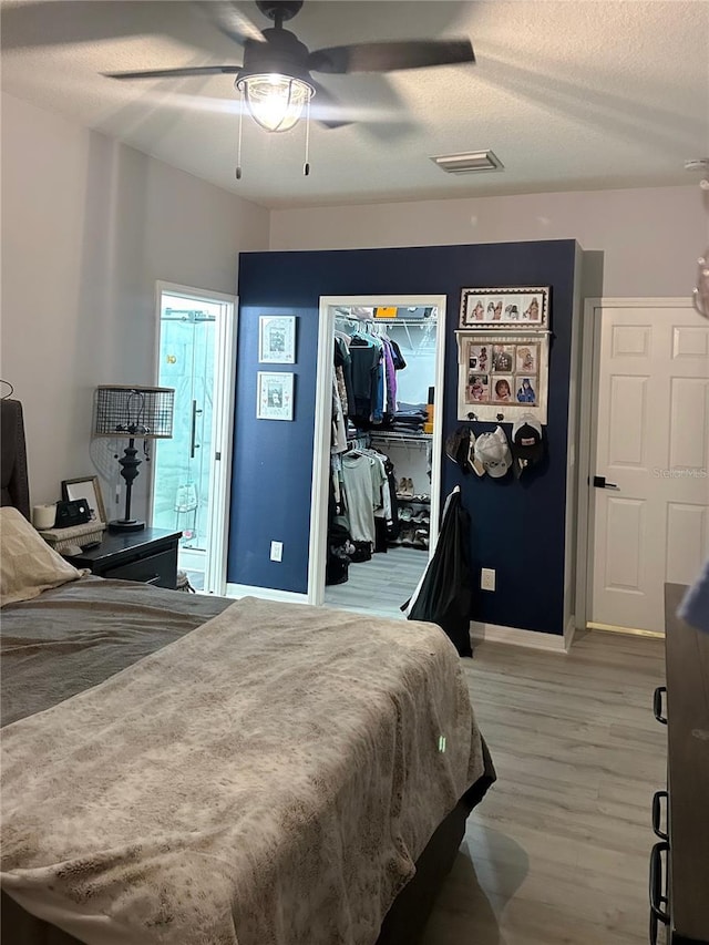 bedroom featuring a textured ceiling, wood-type flooring, ceiling fan, and a closet