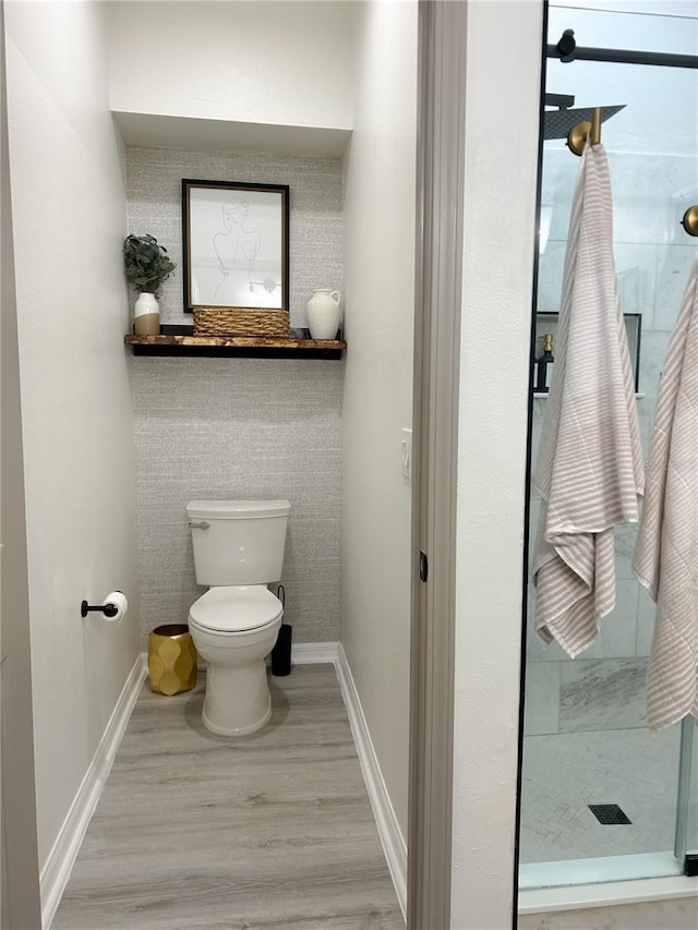 bathroom featuring walk in shower, toilet, and wood-type flooring