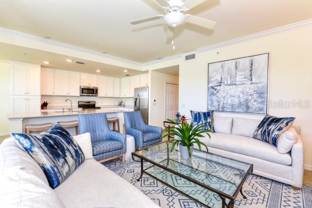 living room featuring sink, ceiling fan, and crown molding