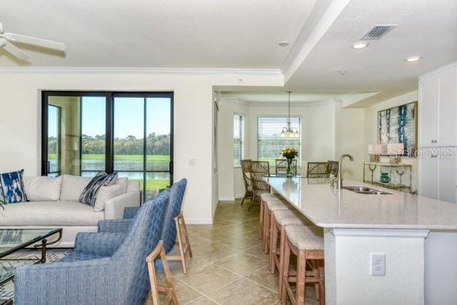 kitchen featuring crown molding, ceiling fan, pendant lighting, sink, and white cabinetry