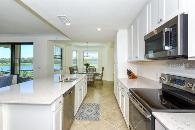 kitchen with stainless steel appliances, a kitchen island with sink, light stone countertops, and sink