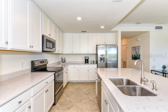 kitchen with sink, stainless steel appliances, white cabinetry, and light stone countertops