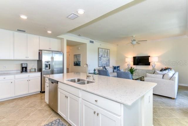 kitchen featuring a center island with sink, white cabinetry, appliances with stainless steel finishes, ceiling fan, and sink