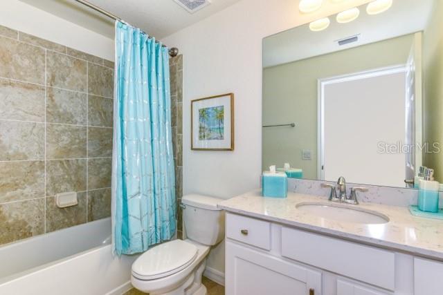 full bathroom featuring shower / tub combo with curtain, vanity, and toilet