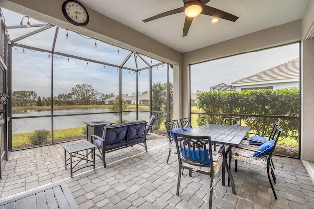 sunroom featuring ceiling fan and a water view