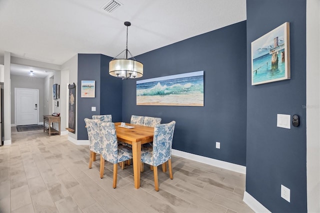 dining space with light hardwood / wood-style flooring and a chandelier