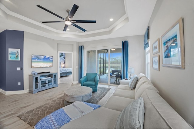 living room featuring hardwood / wood-style floors, ceiling fan, and a tray ceiling