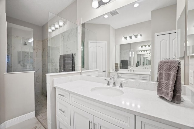 bathroom with a tile shower and vanity