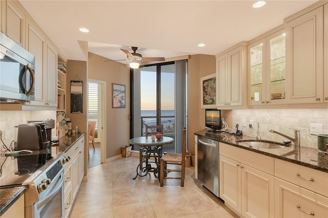 kitchen featuring ceiling fan, dark stone countertops, decorative backsplash, appliances with stainless steel finishes, and cream cabinets